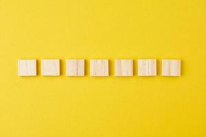 Wooden blocks in row on the yellow background, top view photo