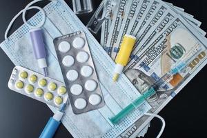 Tablets, protective mask, medical items and dollar bills on dark background