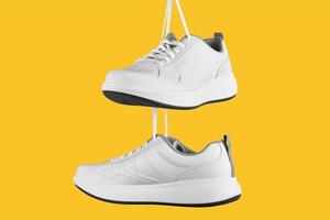 Pair of white male sneakers on yellow background. photo