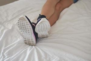 Woman in sport shoes lying on bed and rest after training, closeup photo