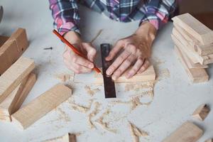 Carpenter hands taking measurement with a pencil of wooden plank. photo