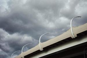 Part of modern bridge with street led lights against cloudy sky. photo