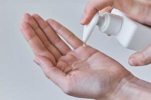 Woman wash hands using sanitizer or antiseptic gel photo