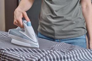 mujer planchando ropa en la tabla de planchar con plancha moderna foto