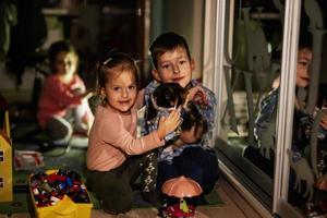 Children playing with kitty at home during a blackout using alternative lighting. photo