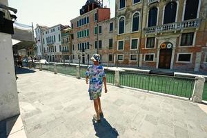 Back of walking boy tourist in panama in canal Venice, Italy. photo
