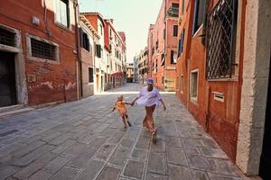 Back of sisters holding hands and run in street Venice, Italy. photo