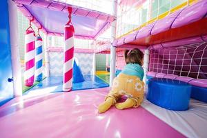 Happy girl crawls at indoor play center playground. photo