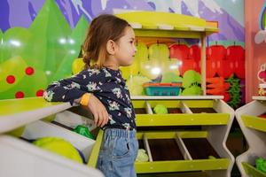 Baby girl playing at indoor kids kitchen playground. photo