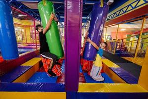 jugando en el patio interior del centro de juegos, hermanos en sacos de boxeo. foto