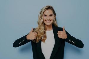 Cheerful girl with blonde hair looking at camera with satisfaction, smiling and showing thumbs up photo