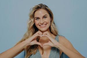 encantadora mujer rubia admitiendo en su amor con el uso del gesto del corazón foto