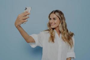 Blonde teenage girl taking selfie while smiling photo