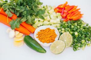 Fresh vegetable assortment on white background. Greenery, cut limes, pepper, carrot, cucumber and lime. Healthy nutrition concept. Vegeterian products photo