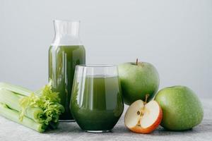 foto de batido verde con cereza y manzana en dos recipientes de vidrio sobre fondo blanco. jugo orgánico saludable. concepto de dieta.