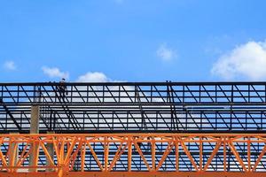 Man welding steel frame-crane-gantry Heavy steel structure for moving large concrete slabs in foundry factory Dangerous slabs are built strong and stable against beautiful evening sky background. photo