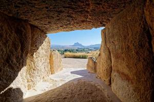 Interior of the megalithic monument Dolmens in Antequera with the natural monument The Lovers' Rock in the background. Touristic travel to Spain. Historic interest and Unesco World Heritage Site. photo