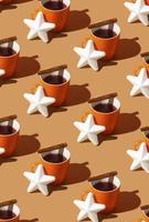 Creative retro pattern made of a tea or coffee cup, white star and cinnamon stick. Winnter mood idea. Comfy Christmas theme. photo