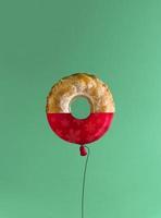 Surreal concept with Bundt cake and red balloon. Green and red Christmas color palette. Minimal composition. photo