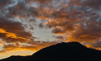 Dawn in the mountains, the first rays of the sun on the red clouds over the mountain. The mountains are in deep shadow, an idea for a background. Mediterranean coast. photo