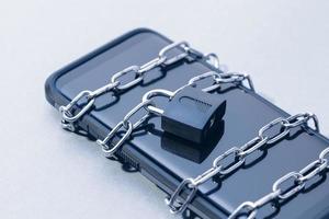 Phone security and data privacy concept. Smartphone locked with chain and padlock photo