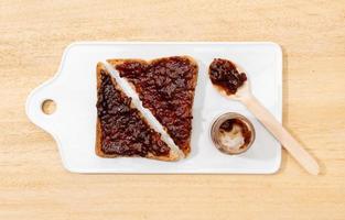 Toast sandwich with raspberry organic jam on wooden table. Flat lay photo