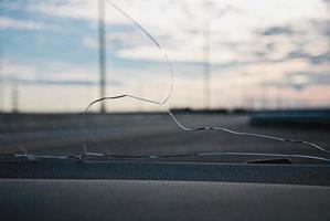 Cracks on car windshield glass hit by stone ejected from under the wheels of another car photo