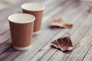 two paper cups standing on wooden table in outdoors cafe photo