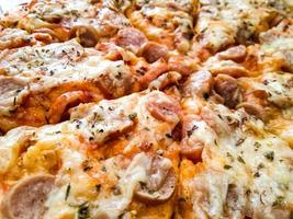 pizza casera con coberturas simples, mozzarella y salchichas en una bandeja de madera foto