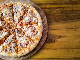 pizza casera con coberturas simples, mozzarella y salchichas en una bandeja de madera foto