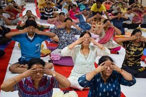 New Delhi, India, June 19 2022 -Group Yoga exercise session for people of different age groups in Balaji Temple, Vivek Vihar, International Yoga Day, Big group of adults attending yoga class in temple photo
