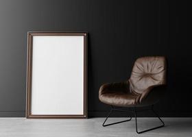 Empty vertical picture frame standing on the floor, with black wall and brown leather armchair. Mock up interior in minimalist style. Free space, copy space for your picture or text. 3D rendering.