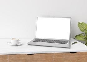 Laptop with blank white screen on wooden table at home or in office. Computer mockup. Free space for app, game, web site presentation. Cozy interior with white wall, cup of coffee, plant. 3D rendering photo