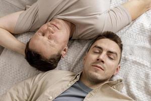 Happy gay couple with casual clothes spending time together at home. Two caucasian men relaxing. Homosexual relationships and alternative love. Cosy interior. photo
