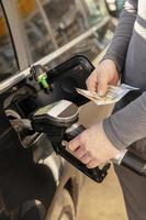 Car refuelling on petrol station. Man refilling car with fuel and holding money, euros. Close up. Gasoline, diesel is getting more expensive. Petrol industry and service. Petrol price and oil crisis. photo