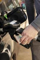 Car refuelling on petrol station. Man refilling car with fuel and holding money, euros. Close up. Gasoline, diesel is getting more expensive. Petrol industry and service. Petrol price and oil crisis. photo