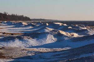 costa del mar báltico con guijarros y hielo al atardecer foto