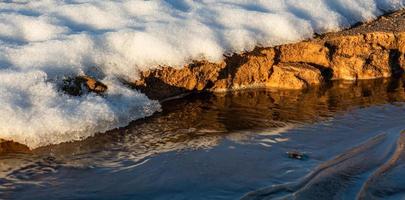 costa del mar báltico con guijarros y hielo al atardecer foto