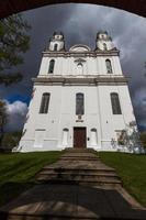 una iglesia católica blanca en un día de verano con nubes oscuras en el fondo foto