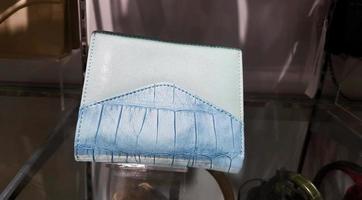 Blue leather wallet on glass shelf at fashion store. Woman bag with modern design at department store. Object or accessory.