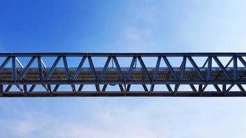Bottom view of stainless steel electrical or communication cable tray with clear blue sky background with copy space. Iron bridge cross to air or heaven and industrial and installed system concept. photo