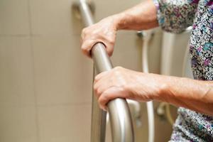 Asian elderly old woman patient use toilet support rail in bathroom, handrail safety grab bar, security in nursing hospital. photo