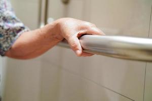 Asian elderly old woman patient use toilet support rail in bathroom, handrail safety grab bar, security in nursing hospital. photo