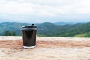 taza de café en la mesa de madera con fondo de vistas a la montaña foto