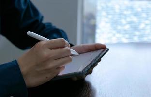 Close up hand holding using pen for writing on touch screen tablet portable concept photo