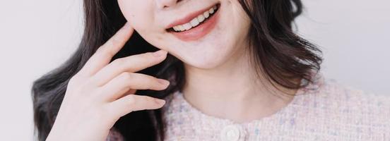 Stomatology concept, partial portrait of girl with strong white teeth looking at camera and smiling, fingers near face. Closeup of young woman at dentist's, studio, indoors photo