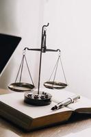 Justice and law concept.Male judge in a courtroom with the gavel, working with, computer and docking keyboard, eyeglasses, on table in morning light photo