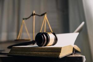 Justice and law concept.Male judge in a courtroom with the gavel, working with, computer and docking keyboard, eyeglasses, on table in morning light photo