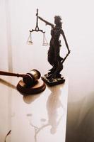 Justice and law concept.Male judge in a courtroom with the gavel, working with, computer and docking keyboard, eyeglasses, on table in morning light photo