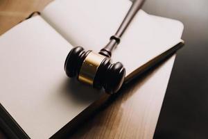 Justice and law concept.Male judge in a courtroom with the gavel, working with, computer and docking keyboard, eyeglasses, on table in morning light photo